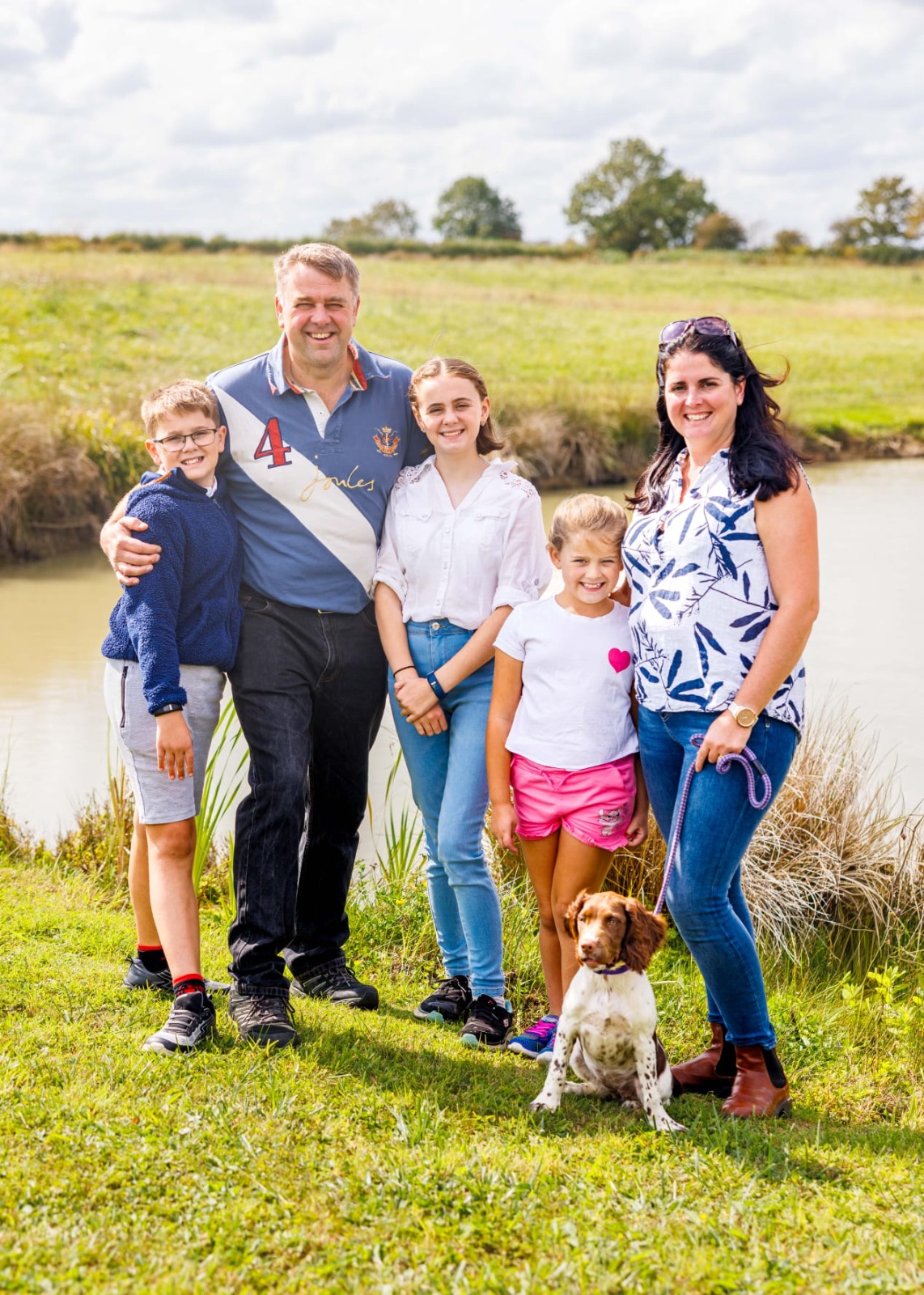 The family at Peacock Farm by the pond with their spaniel